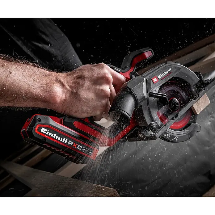 Einhell Professional Power X-Change 18V Akku-Handkreissäge TP-CS 18/136-C Li BL - Solo - 18 V, Ohne Akku, Durchmesser Sägeblatt: 136 mm - Eine Hand bedient eine rot-schwarze Akku-Kreissäge, die ein Holzstück mit fliegendem Sägemehl durchtrennt.