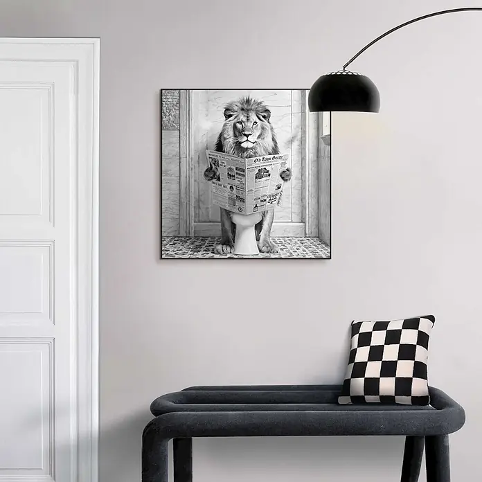 Reinders Bild Slim Frame Black - Lion Break, B x H: 50 x 50 cm - Ein gerahmtes Schwarz-Weiß-Bild eines Löwen, der auf einer Toilette Zeitung liest, über einer Bank.