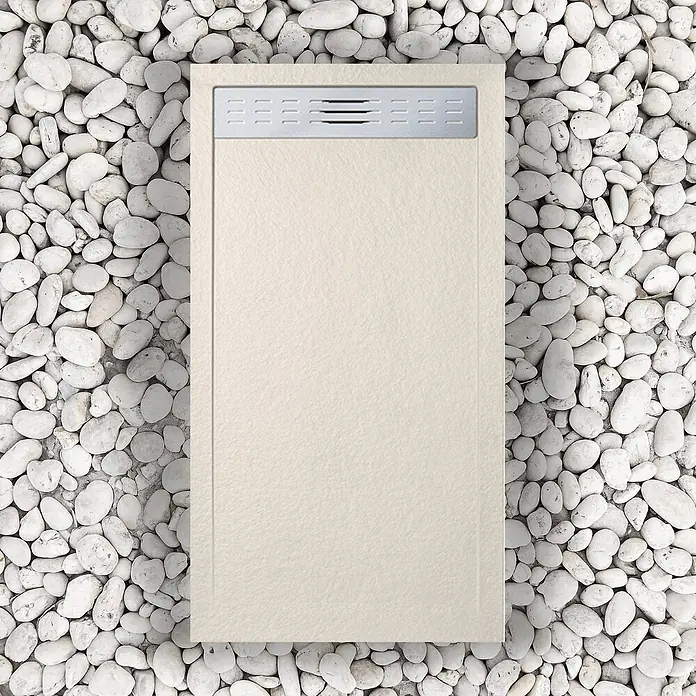 FRASCIO New Tecnology Duschwanne Duschwanne - L x B: 1.200 x 700 mm, Verbundwerkstoff, Warm Beige - Rechteckige, hellbeige Duschwanne mit strukturierter Oberfläche und silbernem Linienablauf auf weißen Kieselsteinen.