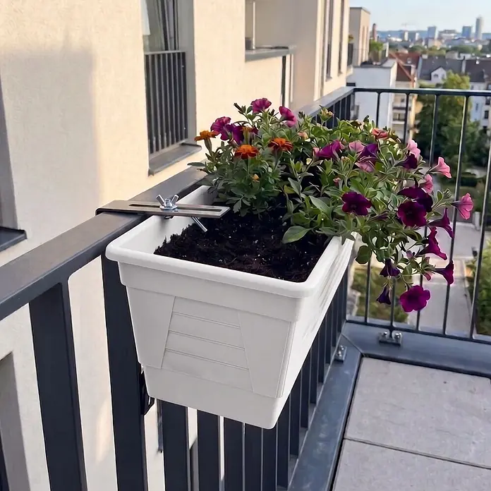 Plastard Pflanzkasten 100 cm selbstwässernd mit Hydroeinsatz & Metallhalterung - Außenmaß (L x B x H): 100 x 21 x 17 cm, Kunststoff, Weiß - Weißer Blumenkasten mit schwarzer Metallhalterung an einem dunkelgrauen Balkongeländer, gefüllt mit bunten Blumen.