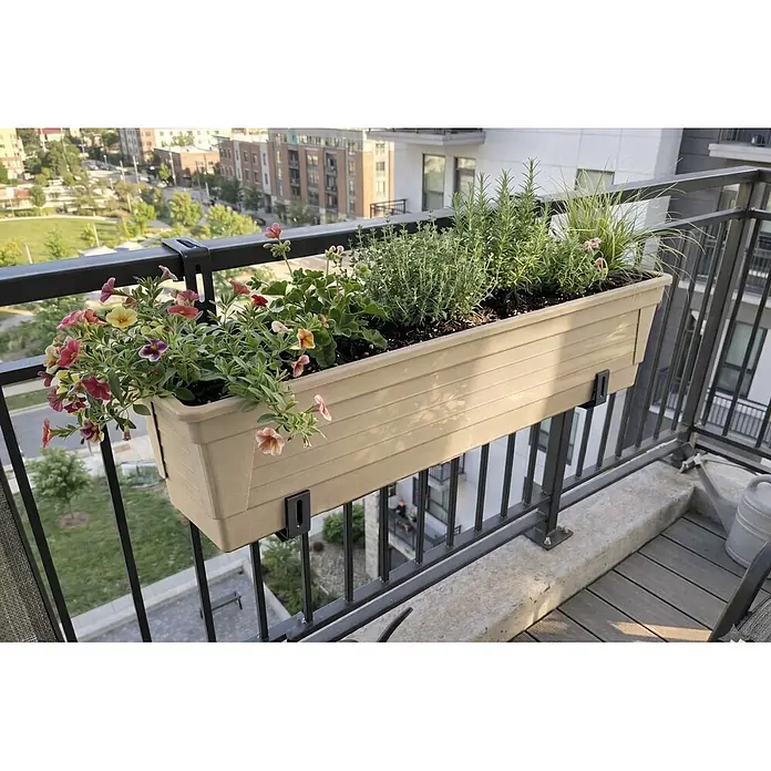 Plastard Pflanzkasten 100 cm selbstwässernd mit Hydroeinsatz & Metallhalterung - Außenmaß (L x B x H): 80 x 21 x 17 cm, Kunststoff, Seidengrau - Beiger Blumenkasten mit schwarzen Halterungen am Balkongeländer, gefüllt mit bunten Blumen und Kräutern.