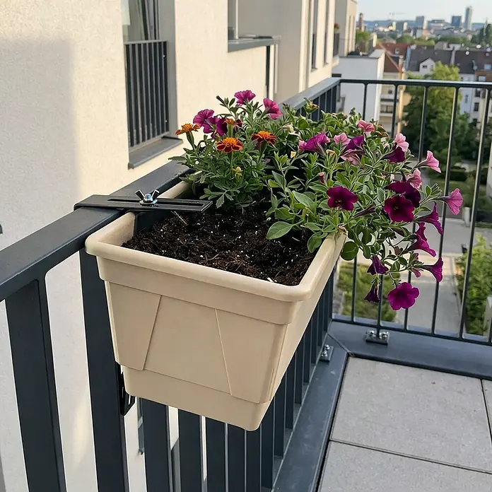 Plastard Pflanzkasten 100 cm selbstwässernd mit Hydroeinsatz & Metallhalterung - Außenmaß (L x B x H): 80 x 21 x 17 cm, Kunststoff, Seidengrau - Beiger Kunststoff-Balkonpflanzkasten mit schwarzer Metallhalterung, gefüllt mit bunten Blumen und Erde, an einem dunkelgrauen Balkongeländer montiert.