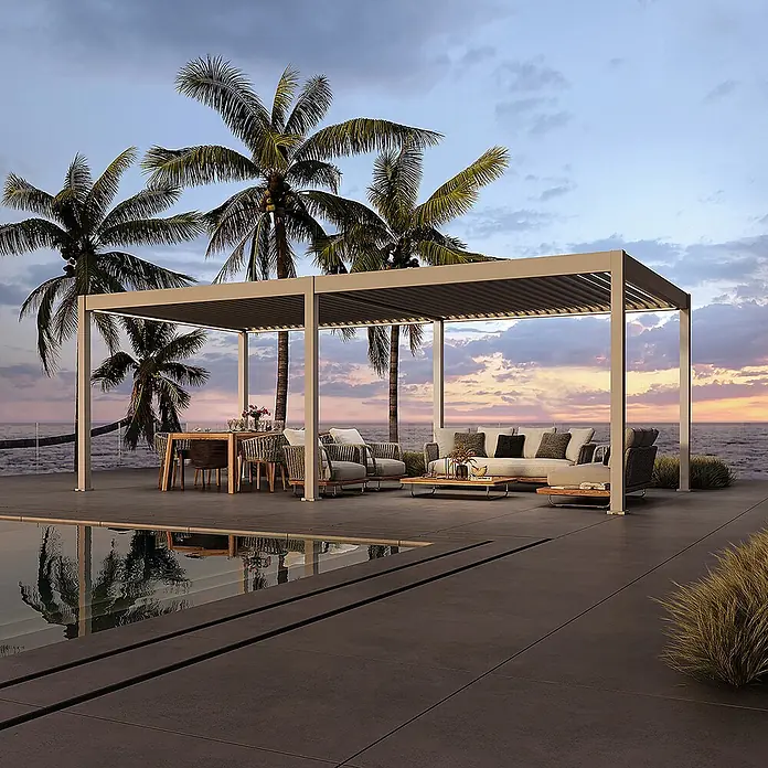 Weide Pergola E-Deluxe Elektrisch freistehend Aluminium 3,6 x 7,2 m Ivory-Sand - B x T: 720 x 360 cm, Farbe Gestell: Sandpapier FinishIvory Sand / RAL Farbcode 7024, Aluminium - Hellgraue Metall-Pergola mit verstellbarem Lamellendach und integrierter LED-Beleuchtung, die einen Ess- und Loungebereich am Meer überdacht.