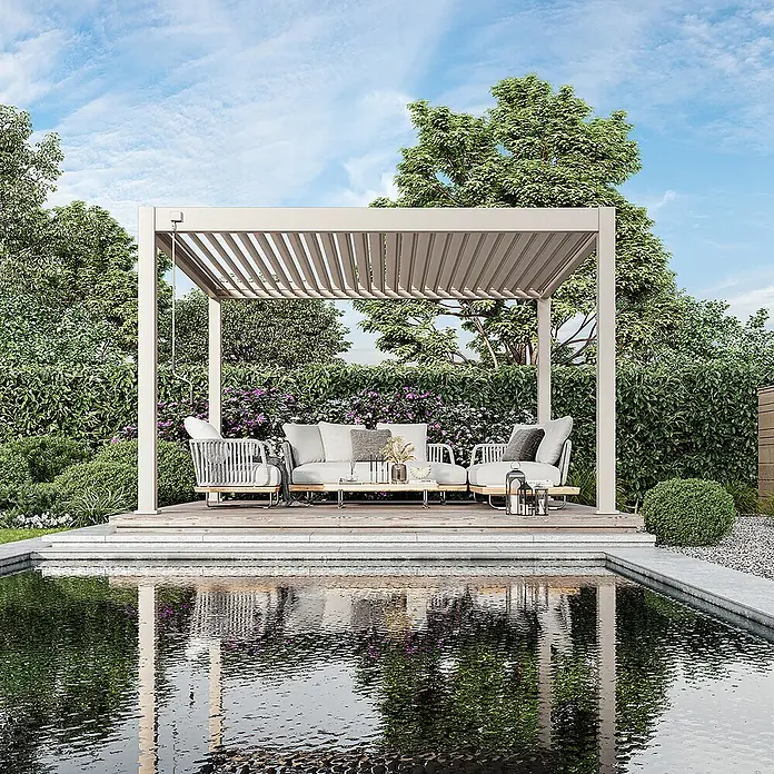 Weide Pergola Deluxe Plus freistehend Aluminium 4 x 4 m Ivory-Sand - B x T: 400 x 400 cm, Farbe Gestell: Sandpapier FinishIvory Sand / RAL Farbcode 7024, Aluminium - Helle Lamellenpergola über einer Sitzgruppe am Teich im Garten.