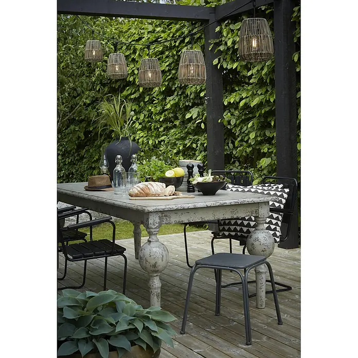 PR Home LED-Lichterkette Saigon -  - Geflochtene Lichterkette hängt über einem Terrassentisch und spendet warmes Umgebungslicht für ein Essen im Freien.