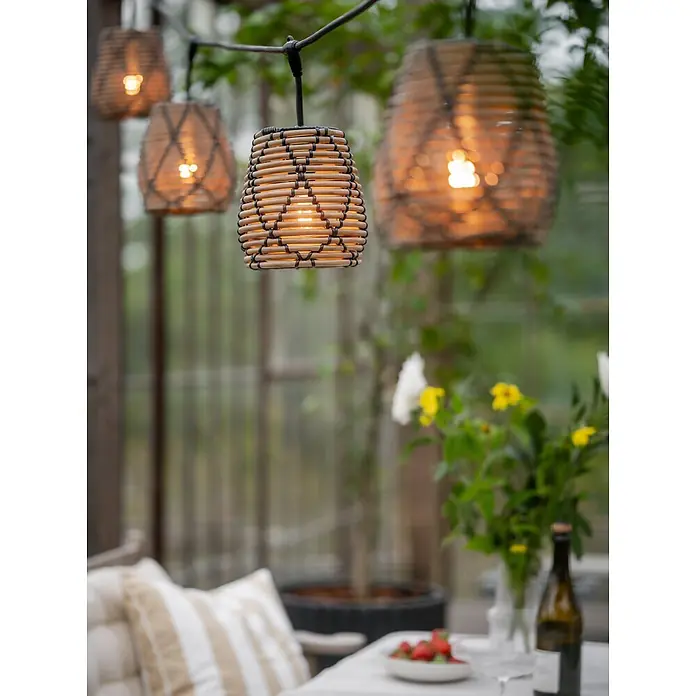 PR Home LED-Lichterkette Flex out -  - Rattan-Optik Lichterkette mit warmem Licht, hängt im Außenbereich über einem Tisch.