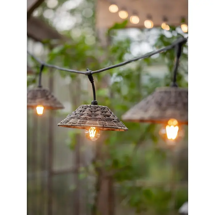 PR Home LED-Lichterkette Flex out -  - Outdoor-Lichterkette mit geflochtenen Schirmen, beleuchtet und in einer Gartenumgebung hängend.