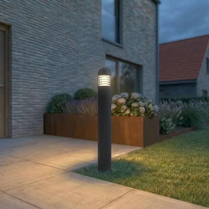 Lucande Außenlaterne Skagena - 12 x 12 x 90 cm - Dunkelgraue Pollerleuchte beleuchtet Weg und Garten neben modernem Haus.