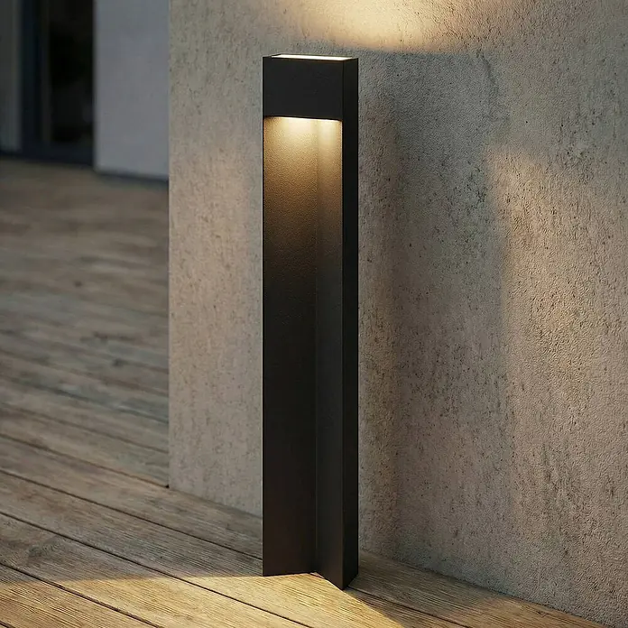 Lucande Außenlaterne Kaholo - 6 x 15 x 90 cm - Schwarze rechteckige Außenleuchte, die eine Holzterrasse und Betonwand warm beleuchtet.