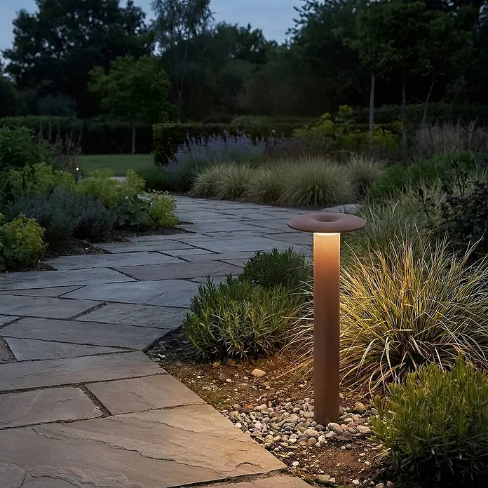 Lucande LED Wegeleuchte in braun, weiß, Gartenlampe -  - Rostfarbene Pollerleuchte beleuchtet Steinweg und Pflanzen im Garten bei Dämmerung.