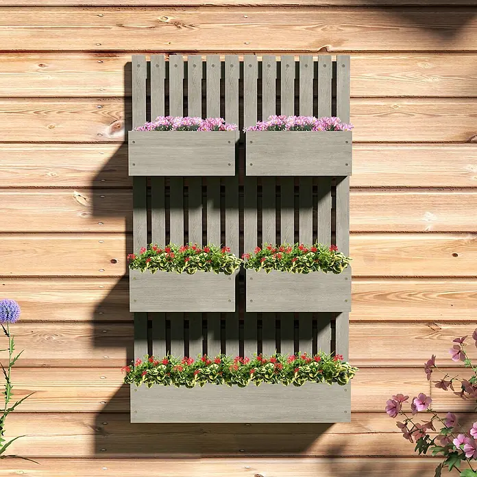Outsunny Hochbeet - 60 x 16 x 100 cm, Holz, Grau - Graues vertikales Holzgartenregal mit drei Pflanzreihen voller rosa und roter Blumen an einer Holzwand.