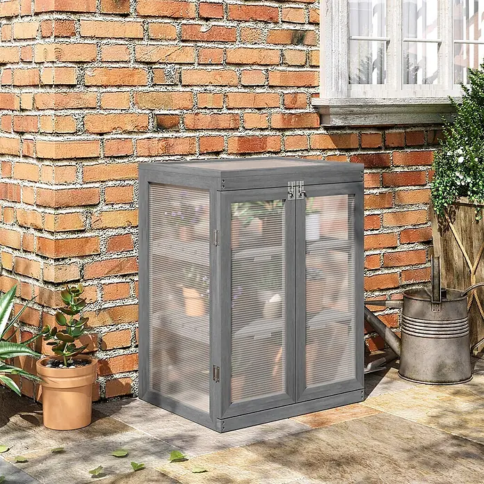 Outsunny Gewächshaus - 58 x 44 cm, Material Seitenwand: Kunststoff, 4 mm, Dunkelgrau - Graues Holz-Frühbeet mit gerippten Klarsichtplatten voller Pflanzen, auf einer Terrasse an einer Ziegelwand.
