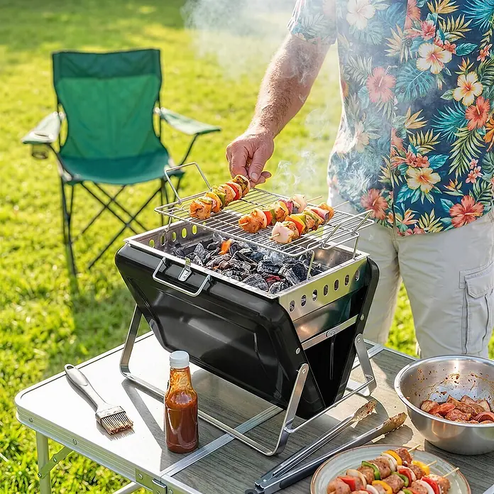 Outsunny Holzkohlegrill - Durchmesser Grillfläche: 32 cm, Schwarz - Kompakter schwarzer und silberner tragbarer Grill wird im Freien zum Garen farbiger Spieße über glühender Kohle verwendet.