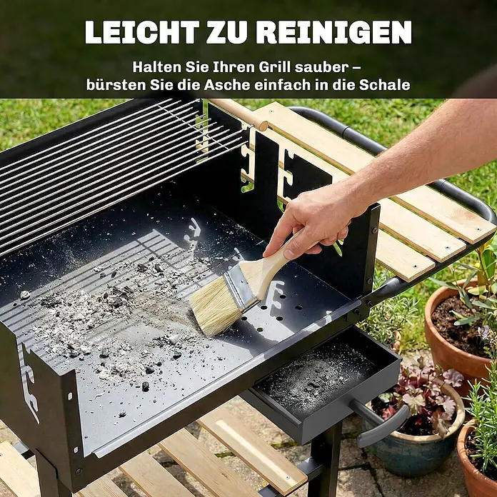 Outsunny Holzkohlegrill - Schwarz - Eine Hand bürstet Asche von einem schwarzen Grill mit Holztischchen in eine herausziehbare Schale, was die einfache Reinigung hervorhebt.