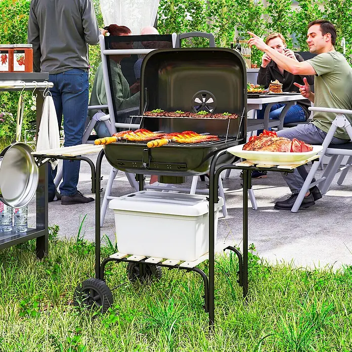 Outsunny Holzkohlegrill - Durchmesser Grillfläche: 46 cm, Schwarz - Schwarzer Holzkohlegrill mit Rädern, Kühlbox und Seitenablagen, aktiv zum Grillen im Freien genutzt.