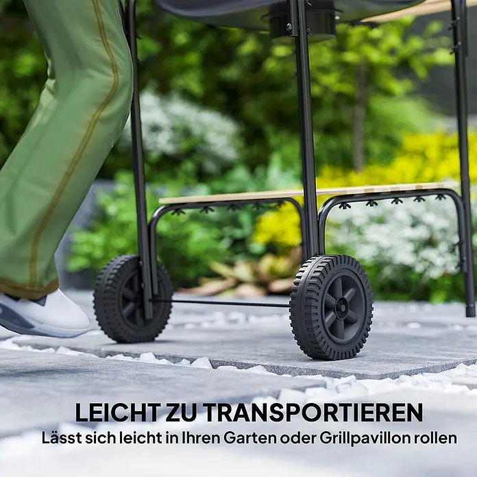 Outsunny Holzkohlegrill - Durchmesser Grillfläche: 46 cm, Schwarz - Schwarz lackierter Grillwagen mit Holzablage und großen Rädern, der von einer Person leicht über einen Gartenweg gerollt wird.