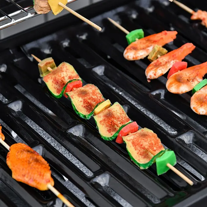 Outsunny Gasgrill - Anzahl Brenner: 1 Stk. - Nahaufnahme eines schwarzen Grills mit Spießen, auf denen Essen gart.