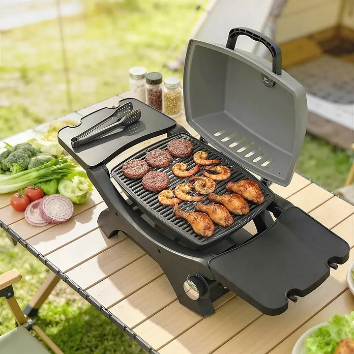 Outsunny Gasgrill - Anzahl Brenner: 1 Stk. - Dunkelgrauer tragbarer Grill kocht Burger, Garnelen und Hähnchenkeulen auf einem Holztisch im Freien.