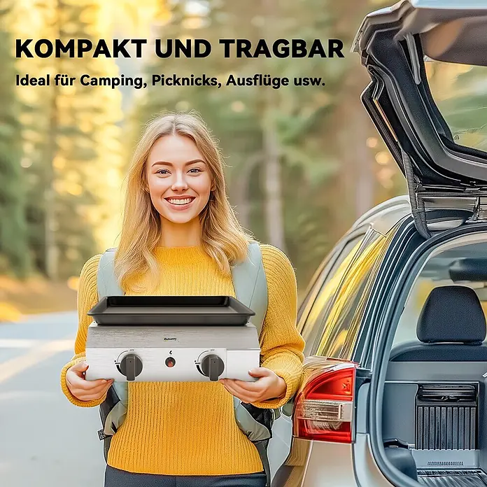 Outsunny Gasgrill - Anzahl Brenner: 2 Stk. - Eine lächelnde Frau hält einen silber-schwarzen tragbaren Grill mit zwei Knöpfen neben einem geöffneten Kofferraum im Freien.