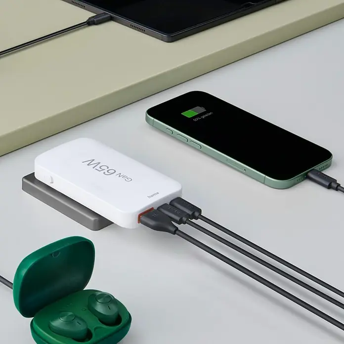 Hama Schnellladegerät 00201976 2x USB-C 1x USB-A flaches Mini PD 65 W WS - Weiß - Weißes Hama GaN 65W Multi-Port-Ladegerät lädt grünes Smartphone und schwarzes Tablet, grüne Ohrhörer daneben.