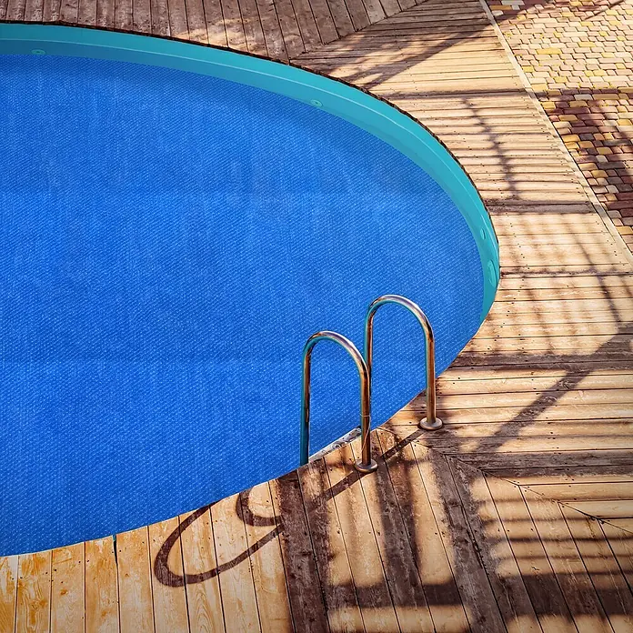 ECD Germany Solarabdeckplane Pool Solarfolie 400µm Solarplane Solarabdeckung Blau - Passend für: Rundpools, Aufstellpools, Swimmingpools, Durchmesser: 500 cm, Material: Kunststoff - Eine blaue, texturierte Poolabdeckung schützt einen runden Swimmingpool, umgeben von Holzterrasse und Pflastersteinen.