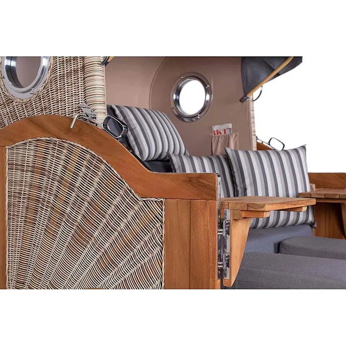 Mr. Deko Strandstuhl Strandkorb Düne Bullauge Teak PE Shell Dessin 544 - Teakholz. Polyrattan, Rückenlehne verstellbar, PE Shell, B x T x H: 125 x 80 x 170 cm - Nahaufnahme eines Strandkorbs aus geflochtenem Rattan und Holz mit gestreiften Kissen, Beistelltisch und Bullauge.