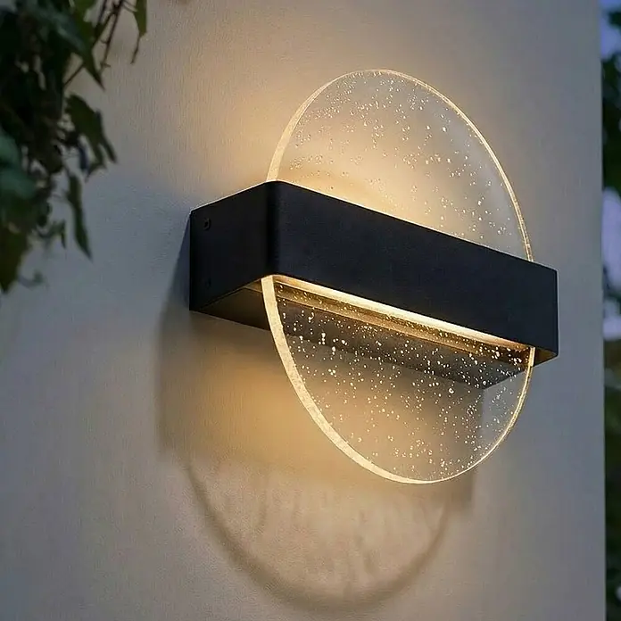 Lucande Außenwandleuchte Narkelo - schwarz, klar / transparent, IP44 - Schwarze Wandleuchte mit texturierter klarer runder Abdeckung, an einer Wand montiert, strahlt warmes Licht aus.