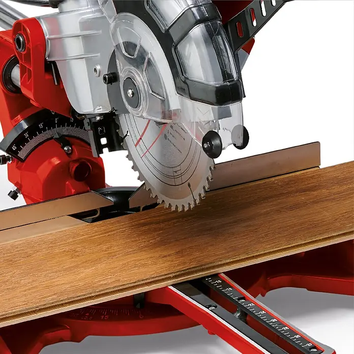 Einhell Kapp- & Gehrungssäge TC-SM 2131/1 Dual - 1.800 W, Durchmesser Sägeblatt: 210 mm, Leerlaufdrehzahl: 4.900 U/min - Rote und silberne Kappsäge mit transparentem Blattschutz, die ein Holzlaminat schneidet.