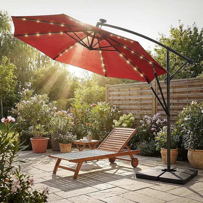 ML-Design Ampelschirm rund Gartenschirm UV50+ Sonnenschutz wasserabweisend 360° drehbar & neigbar - Rot, Durchmesser Bespannung: 300 cm - Roter Ampelschirm mit LED-Beleuchtung spendet Schatten für eine Holzliege und einen Beistelltisch auf einer Terrasse.