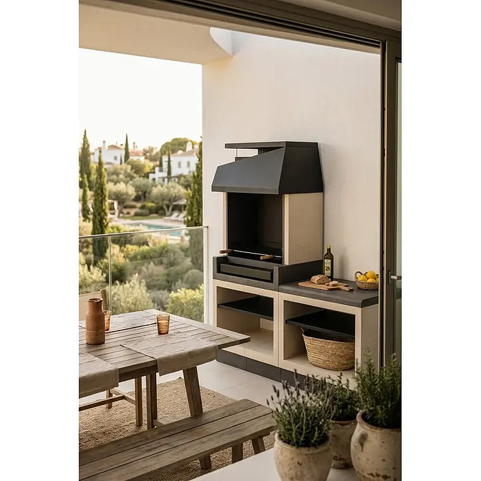 Tuozi Kitaway Holzkohlegrill - Grau/Weiß, B x T x H: 84 x 63 x 206 cm, Mehrstufige Höhenarretierung - Moderne Outdoor-Grilleinheit mit dunkelgrauer Haube und hellem Betonsockel, auf einem Balkon mit Essbereich.