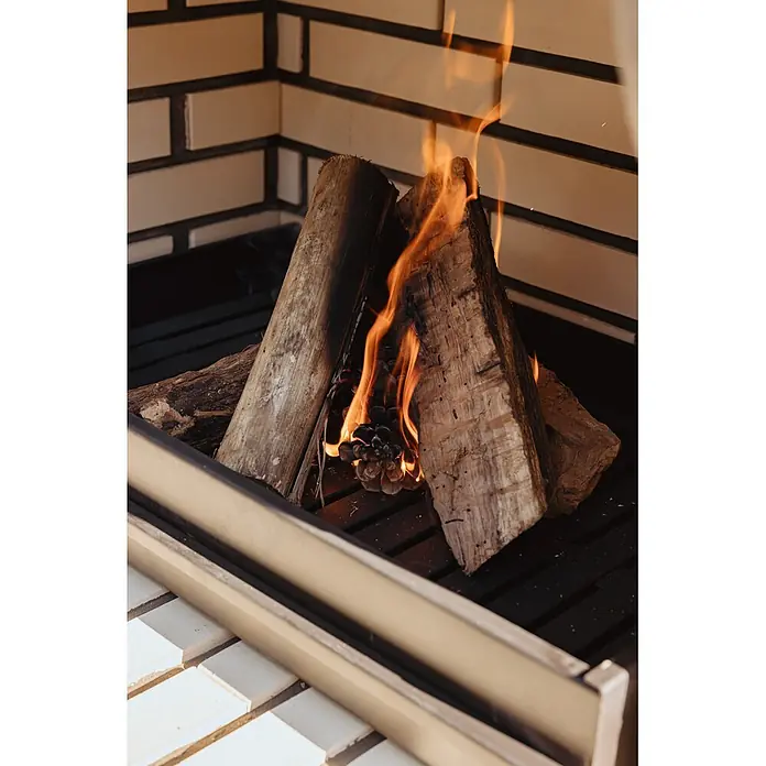 Movelar Bailen Holzkohlegrill - Grillfläche (B x T): 69,5 x 35 cm, Grau/Beige, B x T x H: 165 x 58 x 220 cm - Brennende Holzscheite und ein Tannenzapfen in einem gemauerten Kamin mit lodernden Flammen.