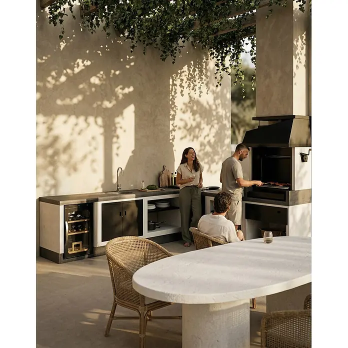 Tuozi Kitaway Outdoorküchen-Modul Seitenschrank - Grau/Weiß, B x T x H: 61 x 63 x 85 cm - Außenküche mit Steinoberflächen, Spüle, Weinkühler und schwarzem Grill, von Personen genutzt.