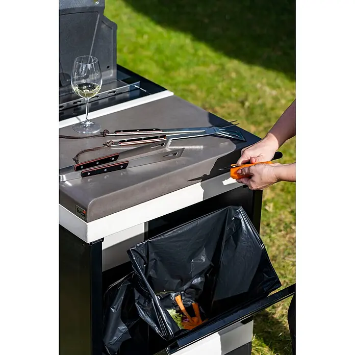 Tuozi Kitaway Outdoorküchen-Modul Abfalleimer - Grau/Weiß/Schwarz, B x T x H: 63 x 42 x 85 cm, Stahl - Outdoor-Küchenvorbereitungstisch mit integriertem Abfalleimer, eine Person schält Gemüse direkt hinein.