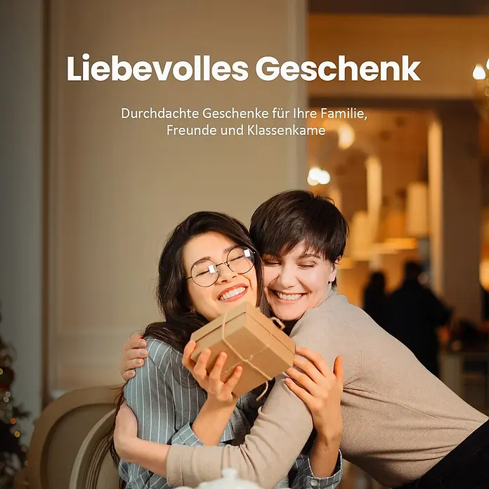 Emke LED-Tischleuchte -  - Zwei glückliche Frauen umarmen sich, eine hält ein kleines, braunes Geschenkpaket.