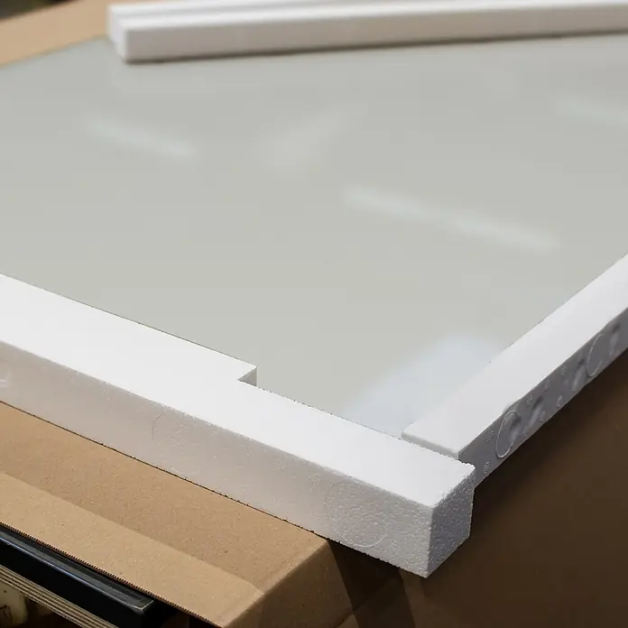 Inova Schiebetür-Komplettset Glas Komplettset wellenförmig mit Griffmuschel + Softclose - 1.025 x 2.200 mm - Hellgraue Platte mit weißer Schaumstoffverpackung auf einem Karton.