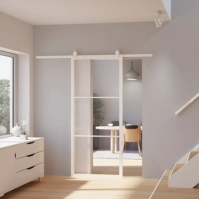 Inova Glasschiebetür Loft Komplettset ESG Klarglas 900 x 2150 mm 3 Felder mit Softclose - 900 x 2.150 mm, Klarglas - Weißes Schiebetürsystem im Scheunentor-Stil mit verglasten Paneelen, das zwei Räume verbindet.