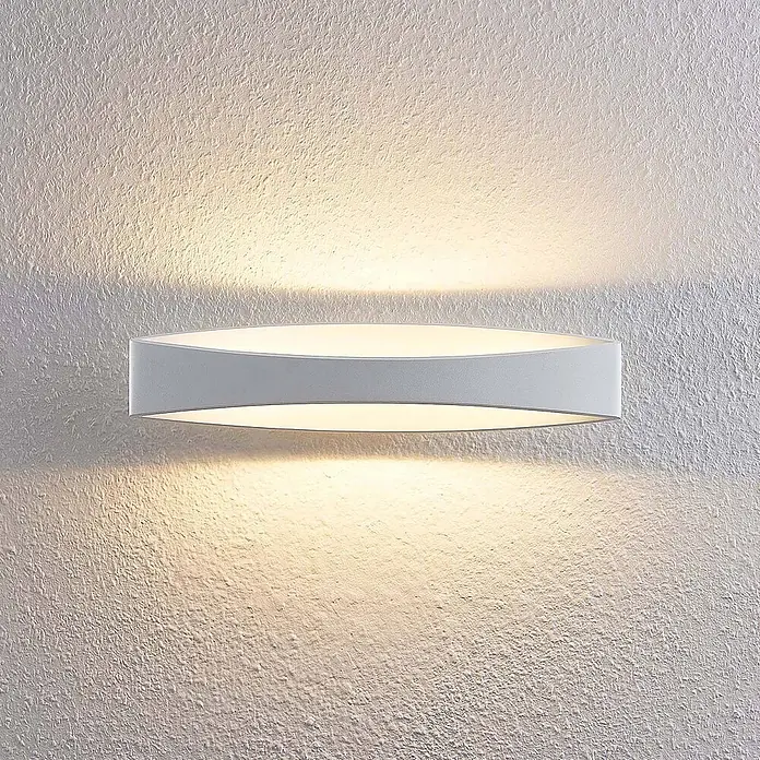 Arcchio Wandleuchte Jelle - weiß / opal, weiß / opal - Moderne weiße ovale Wandleuchte, die warmes Licht nach oben und unten auf eine strukturierte Wand wirft.