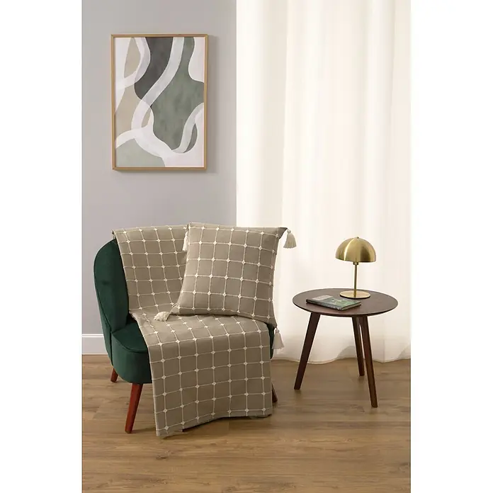Colcha Edna - 260 x 240 cm, 65% algodón y 35% poliéster, Verde - Manta beige y cojín a juego con patrón de cuadrícula blanca y borlas sobre un sillón verde en un salón.