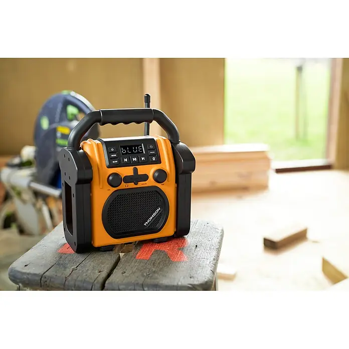 Thomson Radio de batería para la obra WKR60BT - 2.000 mAh - Radio de obra THOMSON robusta, naranja y negra, con asa y pantalla ('BLUE' encendido), sobre madera en un taller.