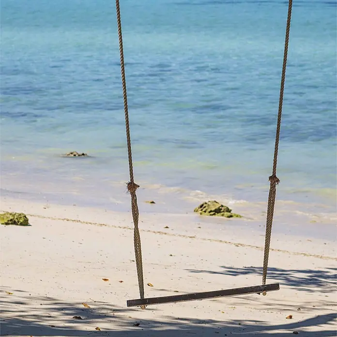 SanDesign Acryl-Verbundplatte - 100 x 250 cm, Tree Swing - Holzschaukel mit Seilaufhängungen an einem Sandstrand am klaren blauen Wasser.