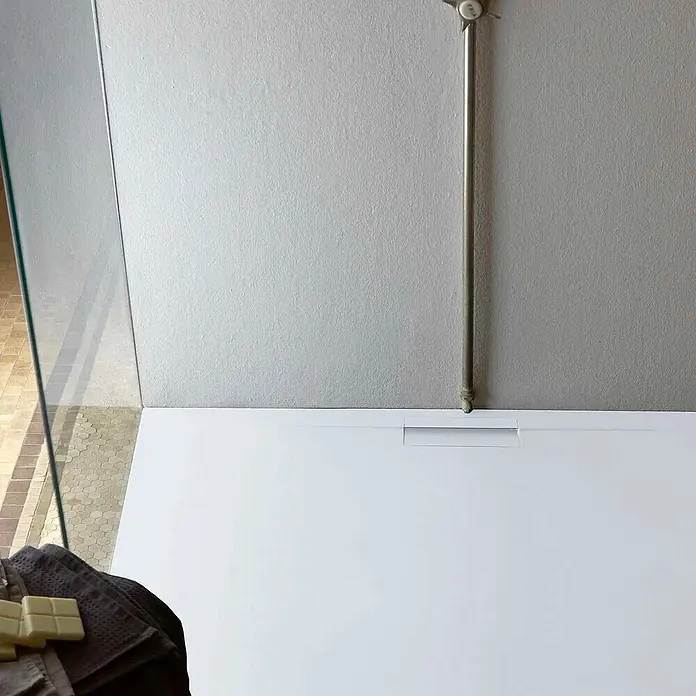 Poalgi Duschwanne Supra - L x B: 180 x 70 cm, Verbundwerkstoff, Blanco - Weiße Duschwanne mit integriertem Linienablauf, zusammen mit einem Duschrohr aus Metall und einer Glaswand.