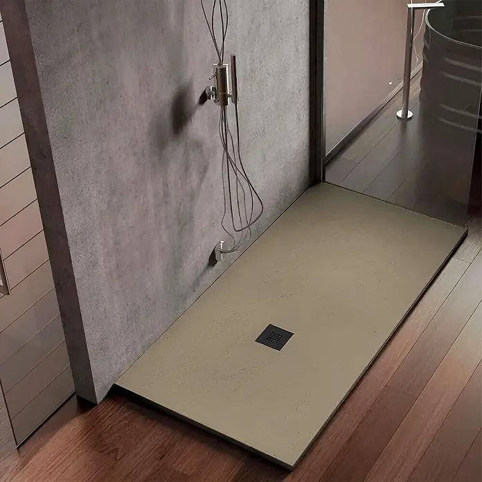 Poalgi Duschwanne Hos's HL - L x B: 120 x 90 cm, Verbundwerkstoff, Beige - Beige, rechteckige Duschwanne mit schwarzem Quadratablauf, bündig in einem Duschbereich mit Holzboden und Betonwand installiert.