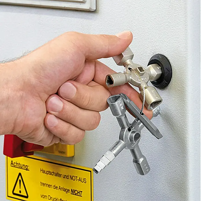 Knipex Universal-Schlüssel Twin Key - 10 Werkzeuge - Ein Multifunktionsschlüssel für Schaltschränke wird an einem Bedienfeld verwendet, gelbe Warnschild im Bild.