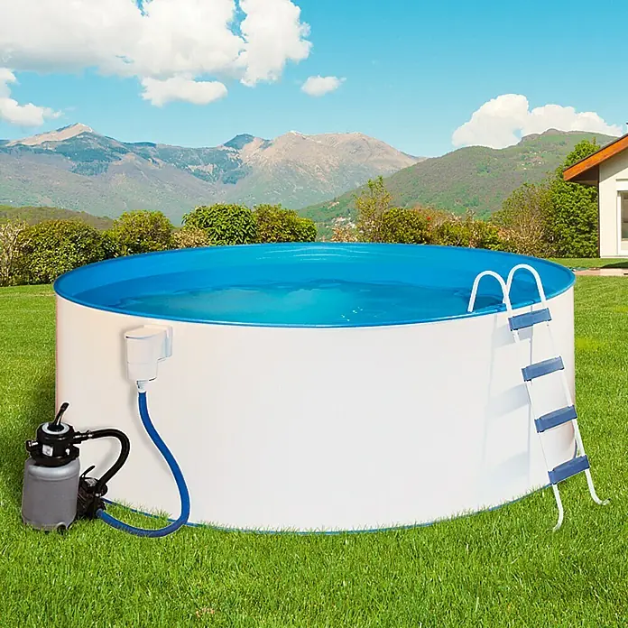 Malibu Stahlwand-Pool Ocean - Ø x H: 450 x 120 cm, Weiß, 18.000 l - Ein großes, rundes Aufstellbecken mit Leiter und Pumpe steht auf einer grünen Wiese vor einer Bergkulisse.