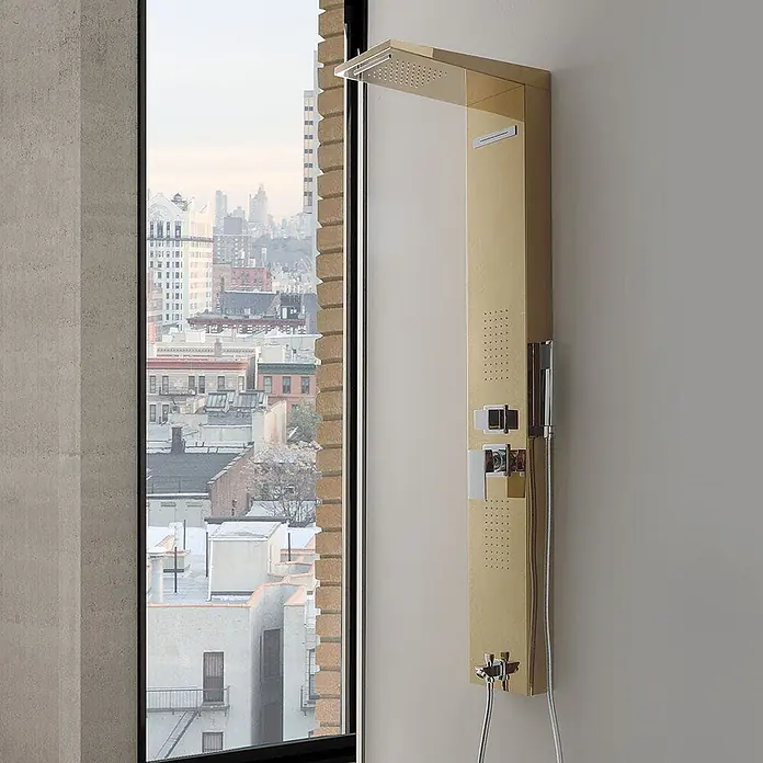 Kiamami Valentina Duschpaneel - Höhe: 1.500 cm, Gold - Goldfarbenes Duschpaneel mit Kopfbrause, Massagedüsen und Handbrause, an einem Fenster mit Stadtblick montiert.