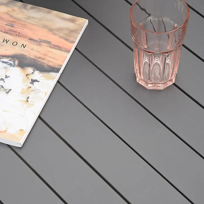 Outsunny Gartentisch-Set - Gesamtumfang: 7 -tlg., Aluminium, Kunststoff, Polyester - Grauer Lattenrosttisch mit einem Buch und einem pinken Glas auf seiner Oberfläche.