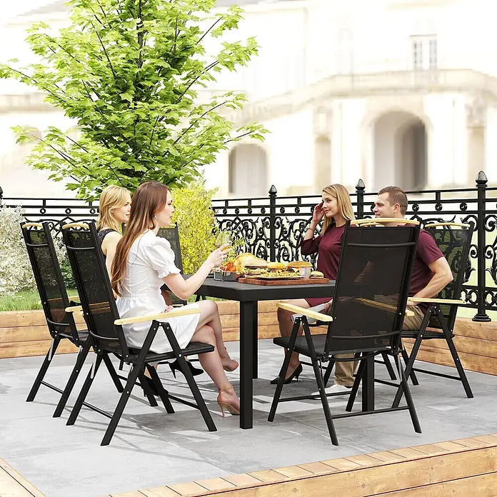 Outsunny Gartentisch-Set - Gesamtumfang: 7 -tlg., Aluminium, Kunststoff, Texteline, Klappbar - Schwarzer Outdoor-Esstisch mit vier schwarzen Netzstühlen mit Holzarmlehnen, von Personen beim Essen auf einer Terrasse genutzt.