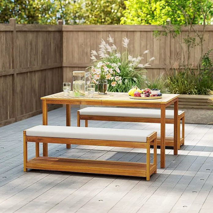 Outsunny Gartentisch-Set - Gesamtumfang: 3 -tlg., L x B x H: 150 x 85 x 75 cm, Akazienholz, Polyester, Schaumstoff - Hölzerne Outdoor-Essgarnitur mit Tisch und zwei Bänken mit weißen Kissen auf einer Terrasse.