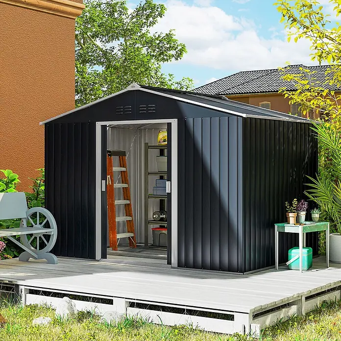 Outsunny Gerätehaus - Außenbreite inkl. Dachüberstand: 277 cm, Außentiefe inkl. Dachüberstand: 195 cm, Stahl, Dunkelgrau - Dunkelgrauer Metall-Gartenschuppen mit offener Tür, zeigt Innenregale und eine Leiter, auf einer Holzterrasse.