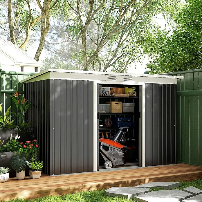 Outsunny Gerätehaus - Außenbreite inkl. Dachüberstand: 280 cm, Außentiefe inkl. Dachüberstand: 130 cm, Stahl, Dunkelgrau - Dunkelgrauer Wellblech-Gartenschuppen mit weißem Rand auf Holzterrasse, Tür offen zeigt Stauraum und Schneefräse.
